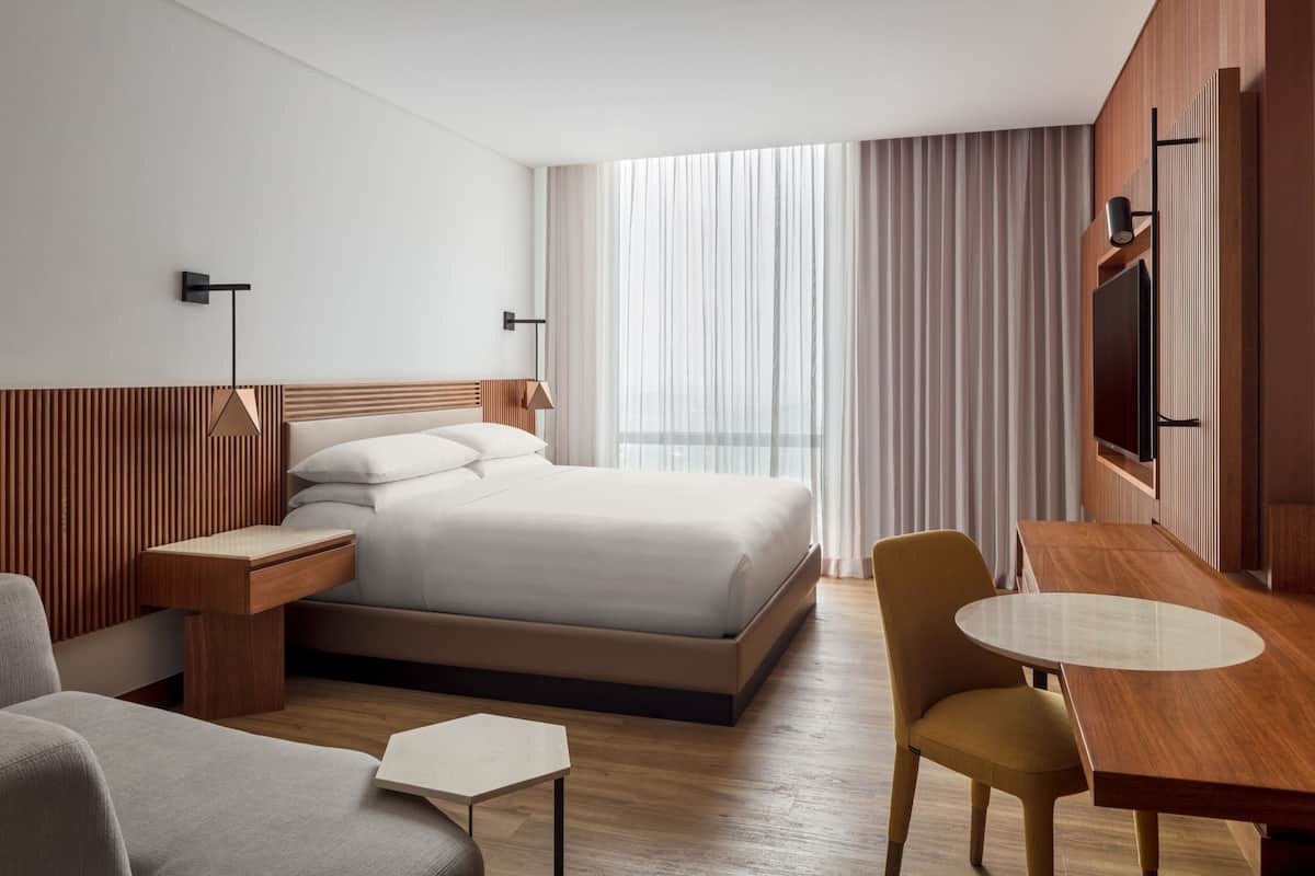 Une chambre d’hôtel moderne équipée d’un grand lit, d’un bureau, d’une chaise et d’un téléviseur.