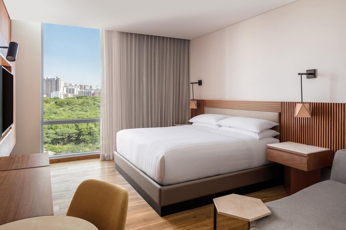 Une chambre d’hôtel moderne avec un grand lit, un bureau, une chaise et une vue sur la ville.