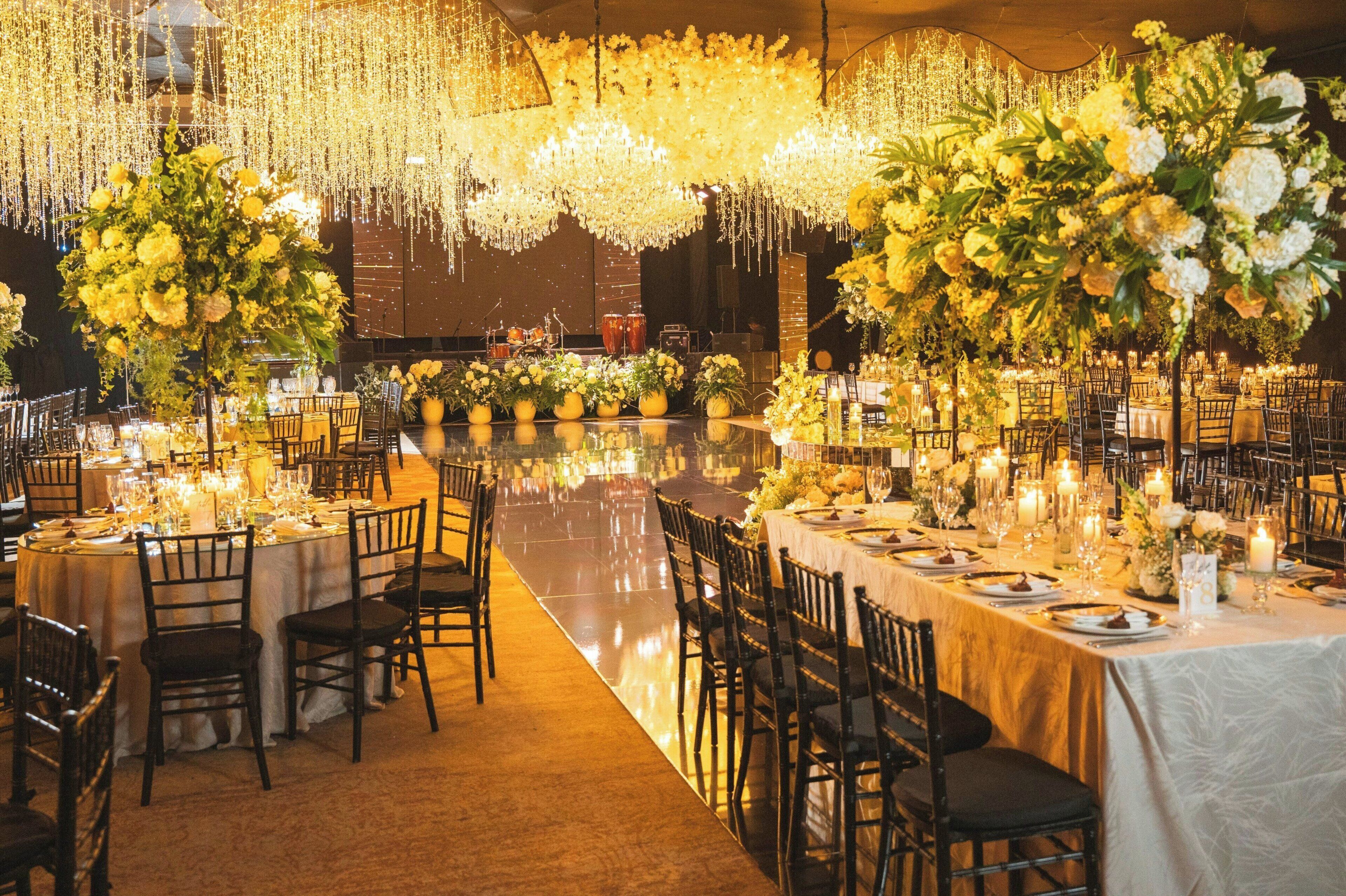 Un salón de banquetes con mesas redondas, sillas y centros de mesa florales.