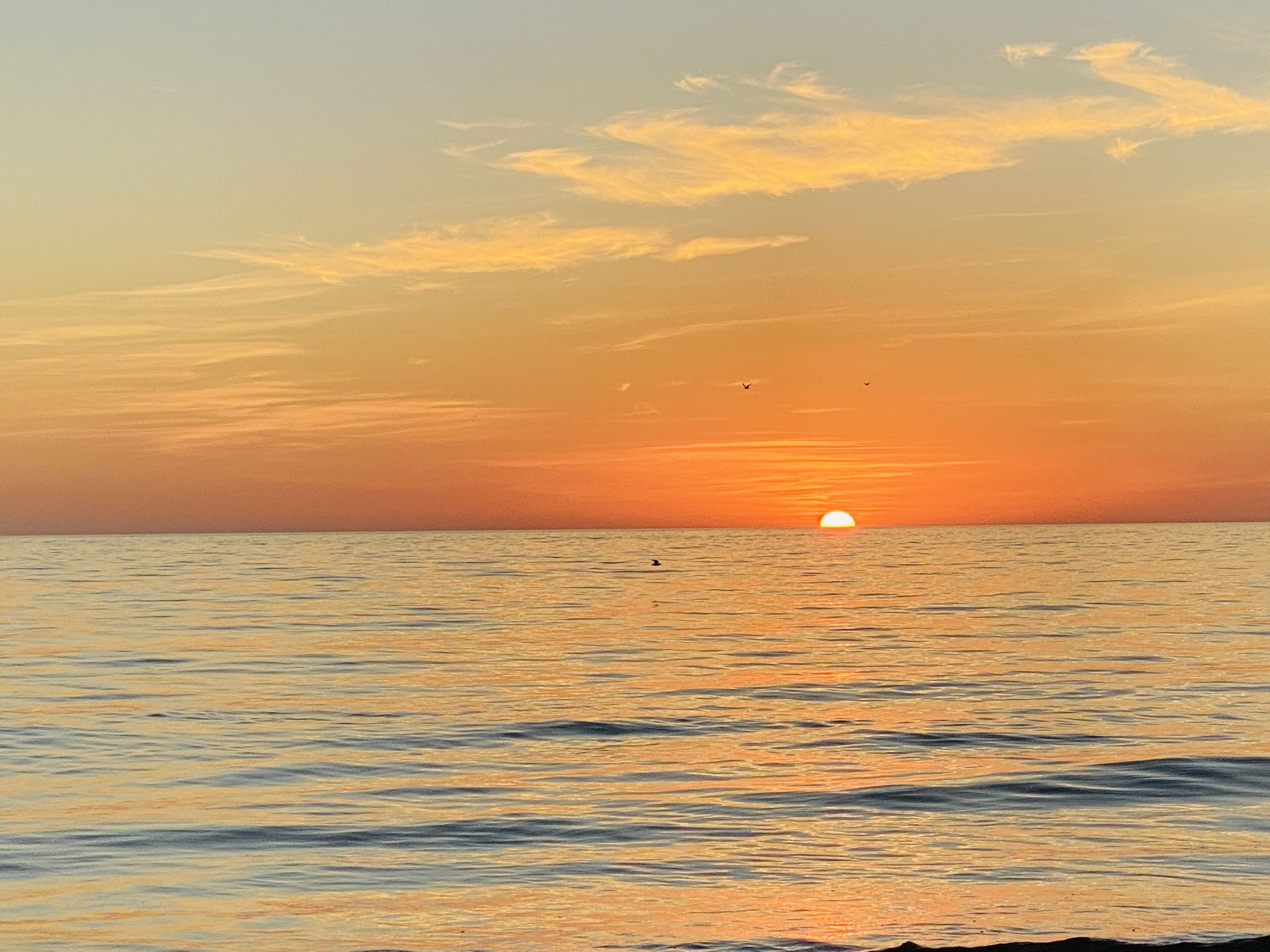 A sunset over a calm sea with a clear horizon.