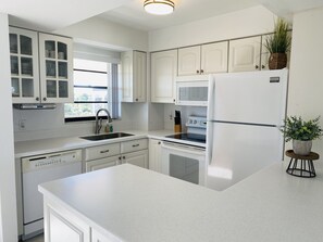 Kitchen features white cabinetry, stainless steel sink, and microwave oven.