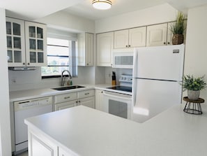 Kitchen features white cabinetry, stainless steel sink, and microwave oven.