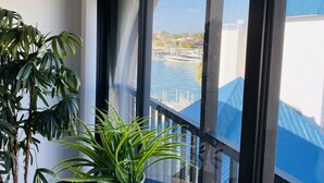 Une plante en pot, placée sur un rebord de fenêtre, d’où l’on peut admirer un port de plaisance et des bâtiments.