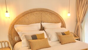 Een bed met een geweven hoofdbord, meerdere kussens en een gele sprei.