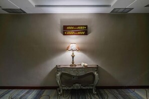 Un pasillo de hotel con indicaciones, una lámpara antigua y una consola clásica.