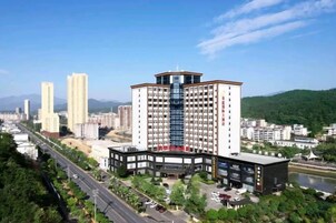 Un hotel de varios pisos con un patio central, rodeado de follaje y un río.