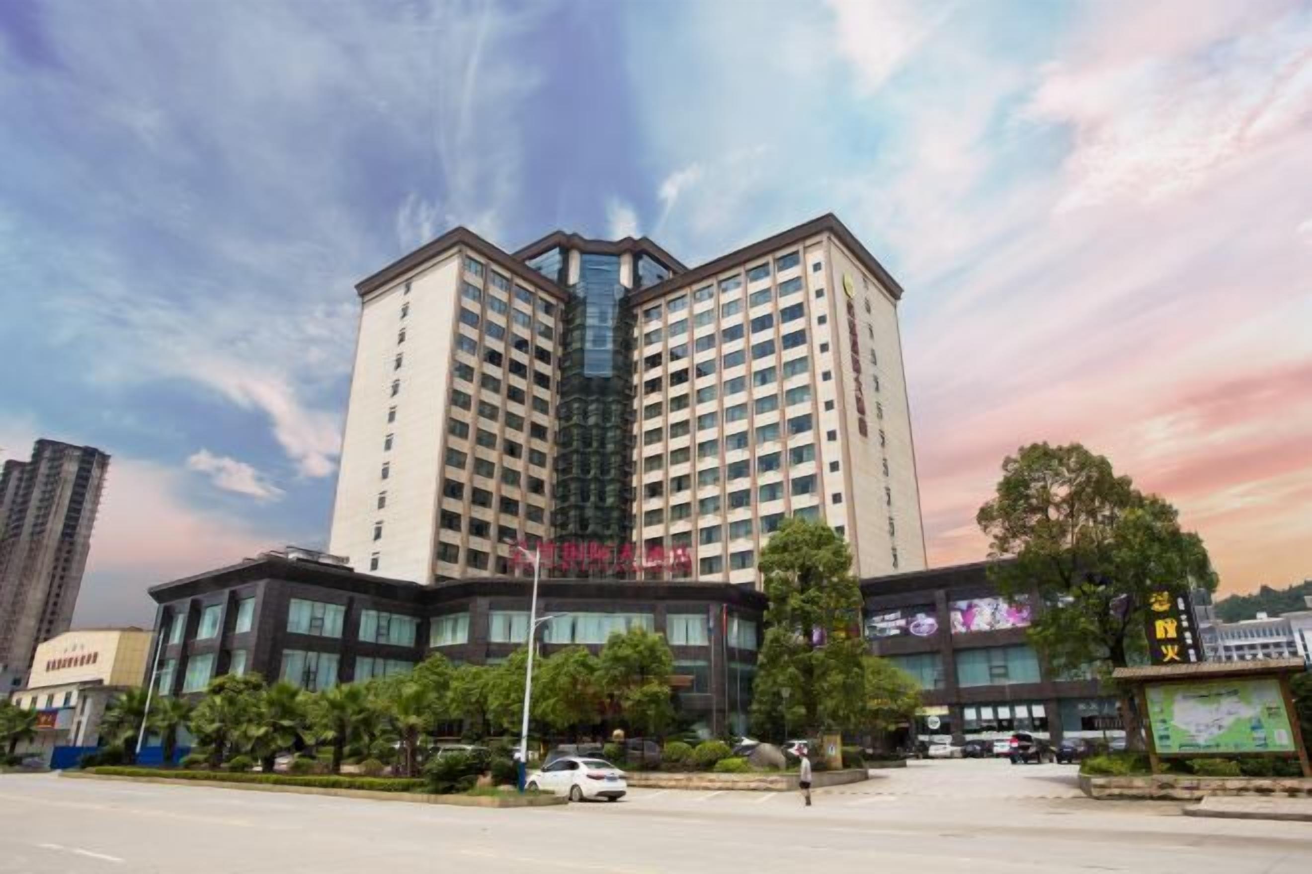 A multi-story hotel with a modern design, featuring a prominent glass facade and a symmetrical structure.