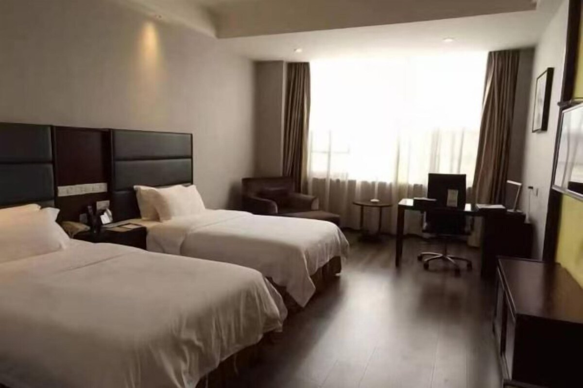Habitació d'hotel amb dos llits, una taula de treball, una cadira i una televisió.