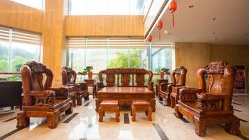 A lobby with a wooden sofa set, a coffee table, and a TV.