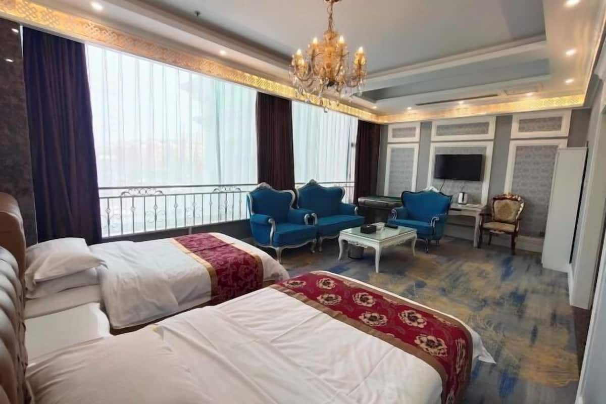 A hotel room with two beds, a sofa, a coffee table, a TV, and a balcony.