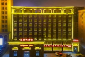 Un edificio con varios pisos, amplias ventanas y señalización iluminada.
