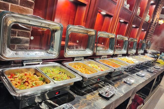 A buffet with multiple food stations, each with a clear glass cover.