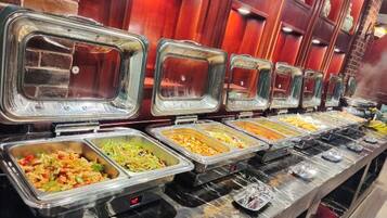 A buffet with multiple food stations, each with a clear glass cover.