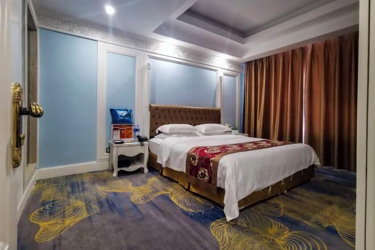 Una habitación de hotel con cama, mesita de noche y teléfono instalado en la pared.