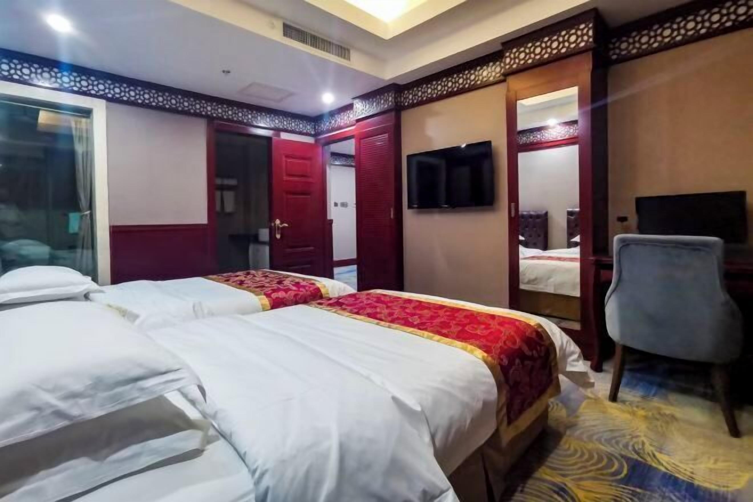 A hotel room with two beds, a TV, a chair, and a wardrobe.