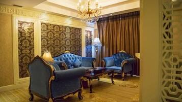 A room with two blue upholstered armchairs, a wooden coffee table, and a chandelier.