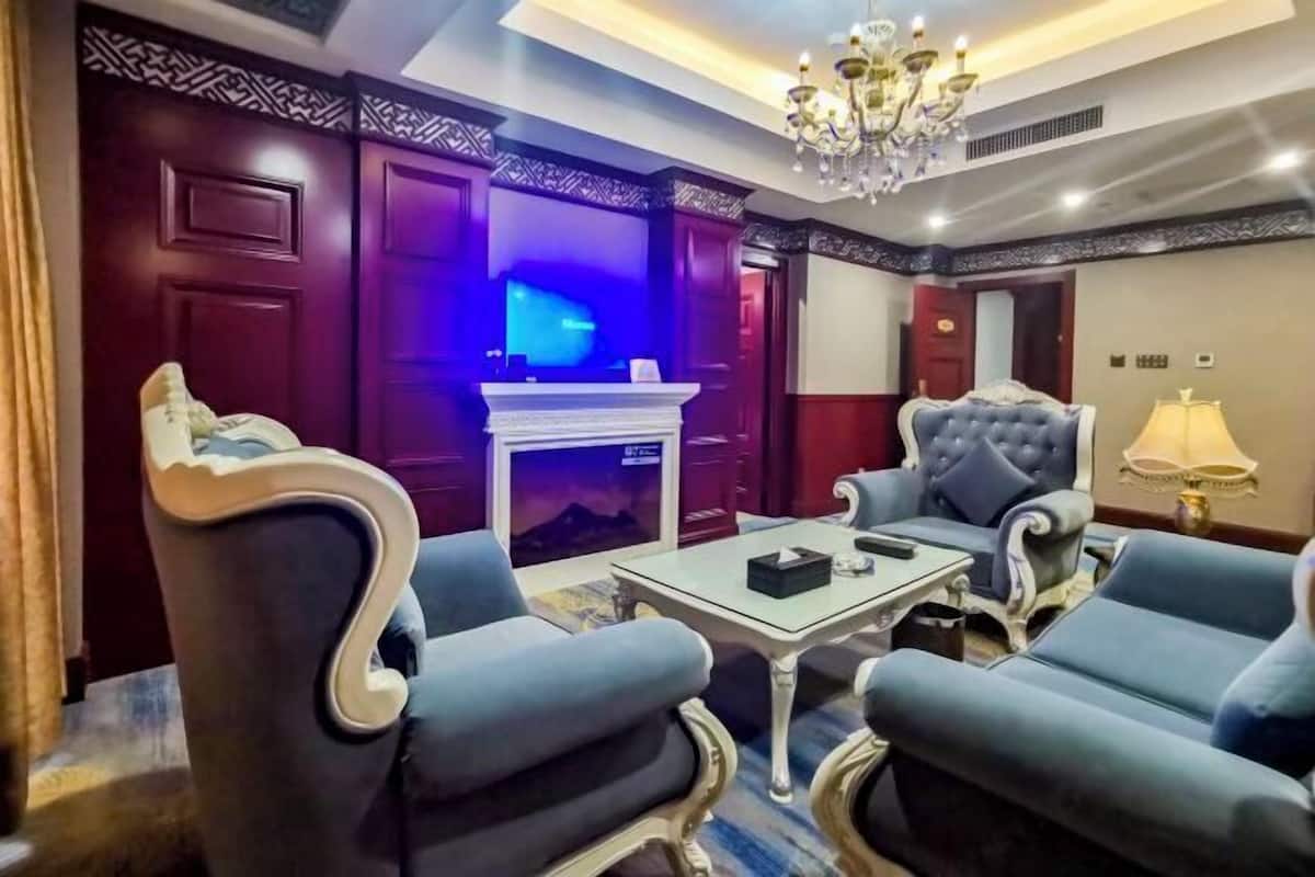 A room with a fireplace, a chandelier, and blue upholstered furniture.