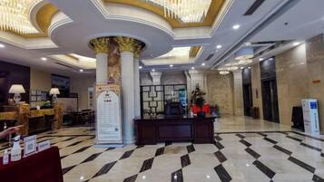 A hotel lobby with a reception desk, a large column, and a check-in counter.