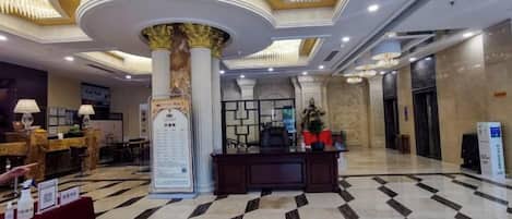 Un vestíbulo de hotel con una recepción, una columna grande y un mostrador de registro.