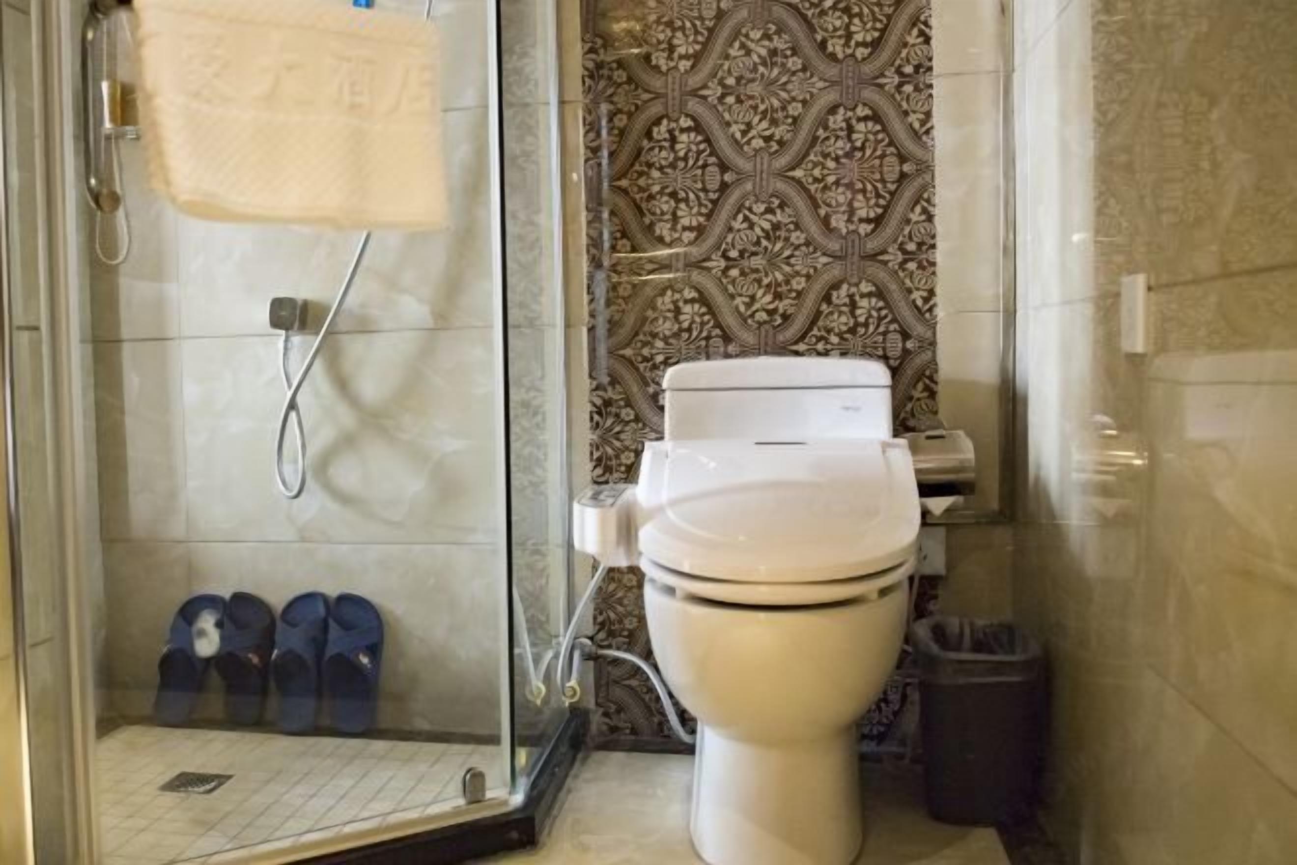 Un baño con inodoro, cabina de ducha y pared con estampado.