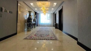 Un pasillo de hotel con suelo de mármol, alfombra floral y un candelabro.