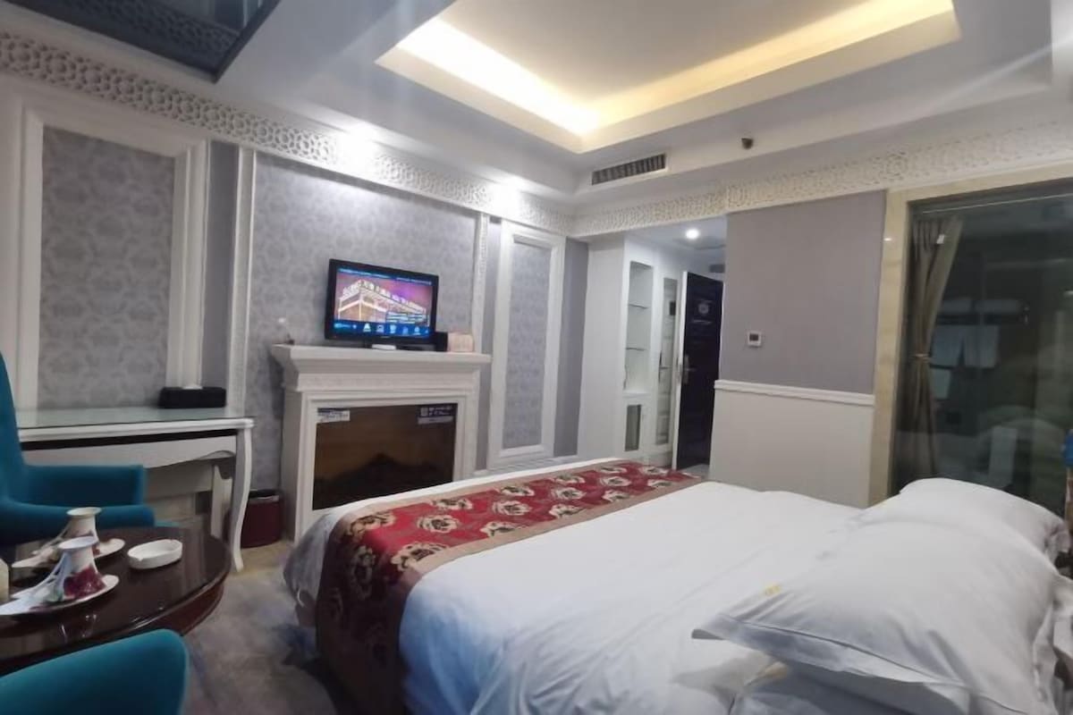 Habitación de hotel con cama, televisión, chimenea y zona de comedor con sillas.