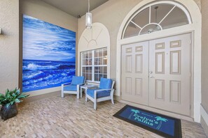 Relax in a serene outdoor space with an entrance, vibrant ocean mural, and comfortable seating.