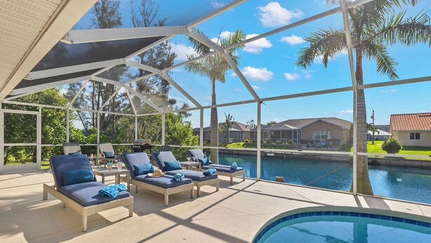 A poolside area with lounge chairs and a pool. - Great for kids! Paddle boards, bikes, kayaks & pet friendly! Villa Evelyn's Palms - SWFL Rentals (Cape Coral)