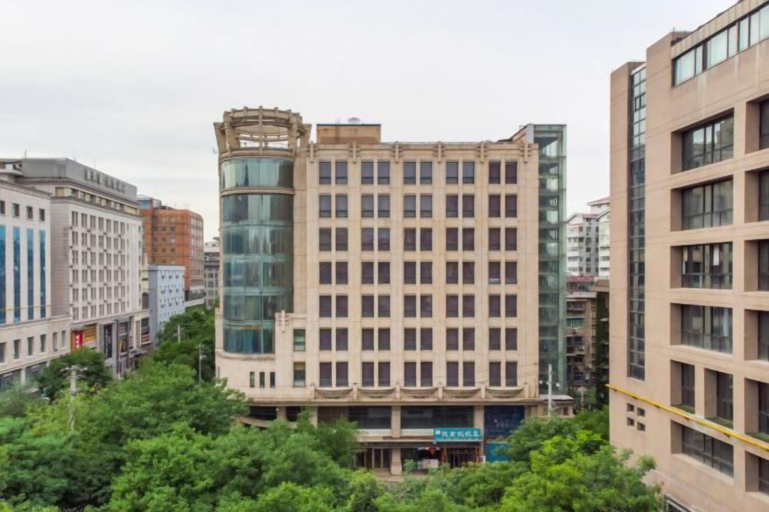 A multi-story hotel with a central glass facade, surrounded by other buildings.
