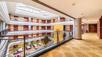 Un vestíbulo de hotel de varios niveles con un patio central, balcones y una imponente escalera.