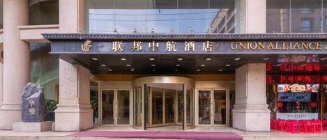 A hotel entrance with a revolving door, a marquee sign, and a glass facade.