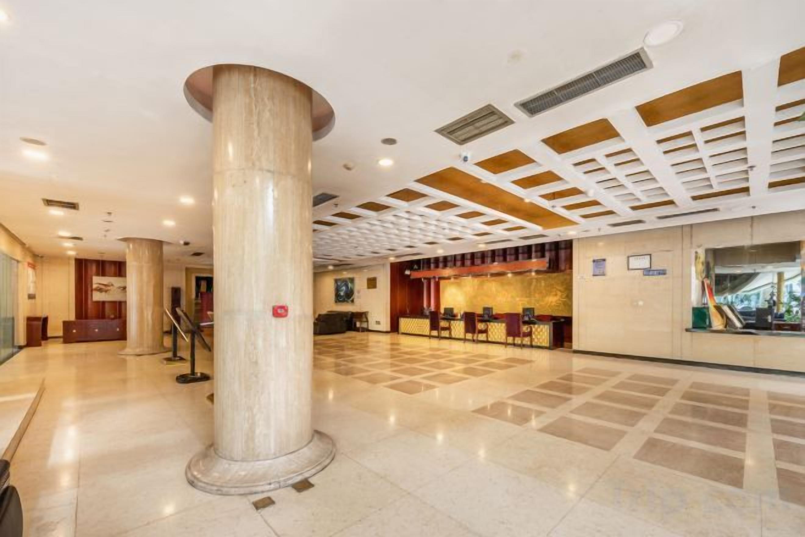 Un vestíbulo amplio con una columna central imponente, un mostrador de recepción y una mesa de registro.