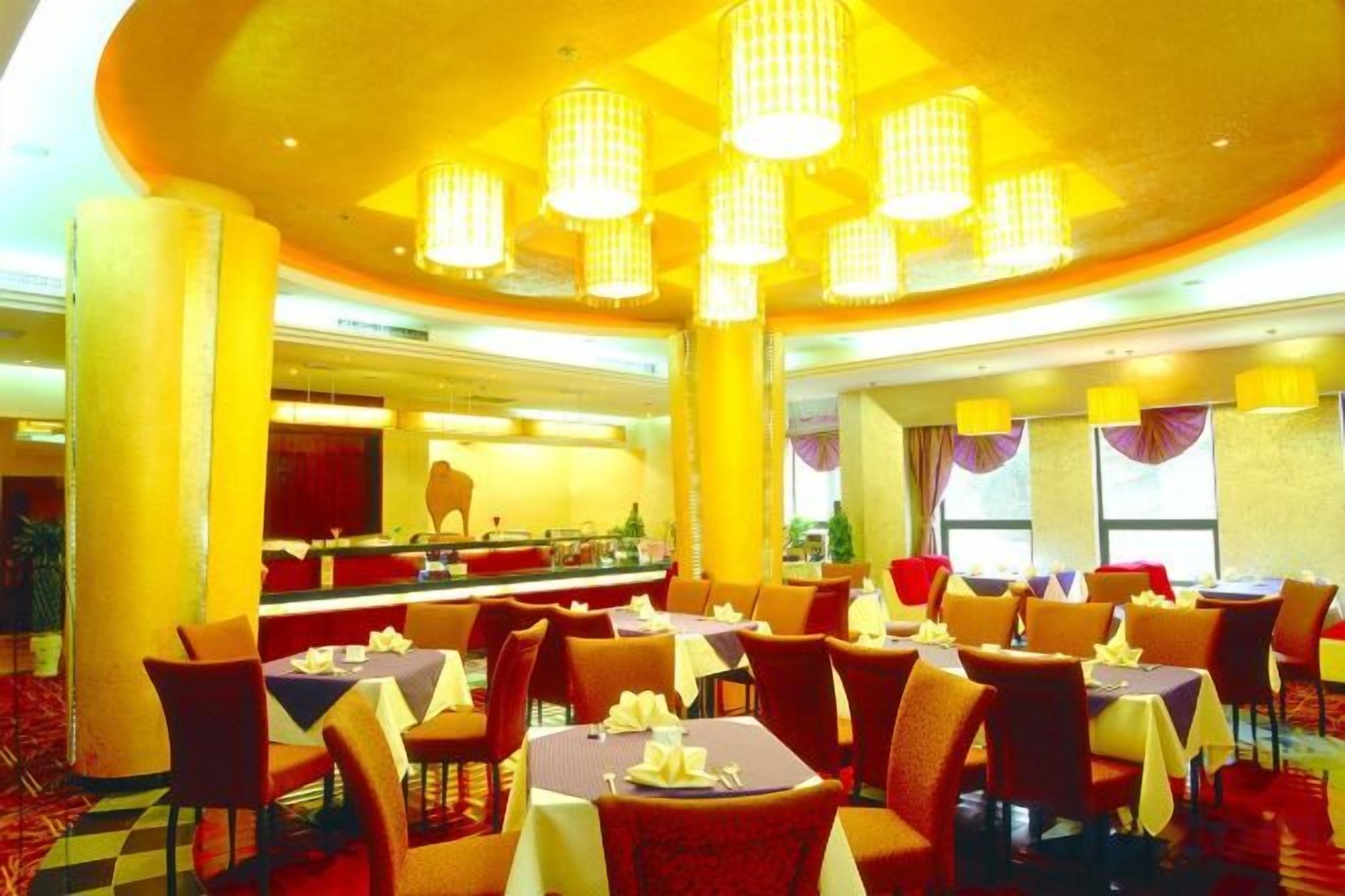 Un comedor de hotel con varias mesas y sillas, un mostrador de buffet y una gran lámpara de araña.