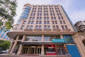 A multi-story building with a prominent entrance, a sign for a business, and a blue storefront. - Federation AVIC Business Hotel (Xi'an Bell and Drum Tower) (Xi'an)