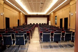 Un salón de conferencias con filas de sillas orientadas hacia un escenario.