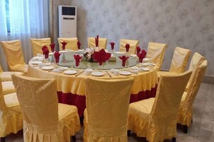 Una mesa de comedor redonda con platos blancos y flores rojas, rodeada de sillas con fundas amarillas.
