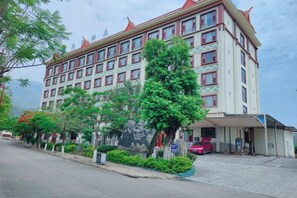 A multi-story hotel with a traditional architectural style, featuring a large entrance and a parking area.