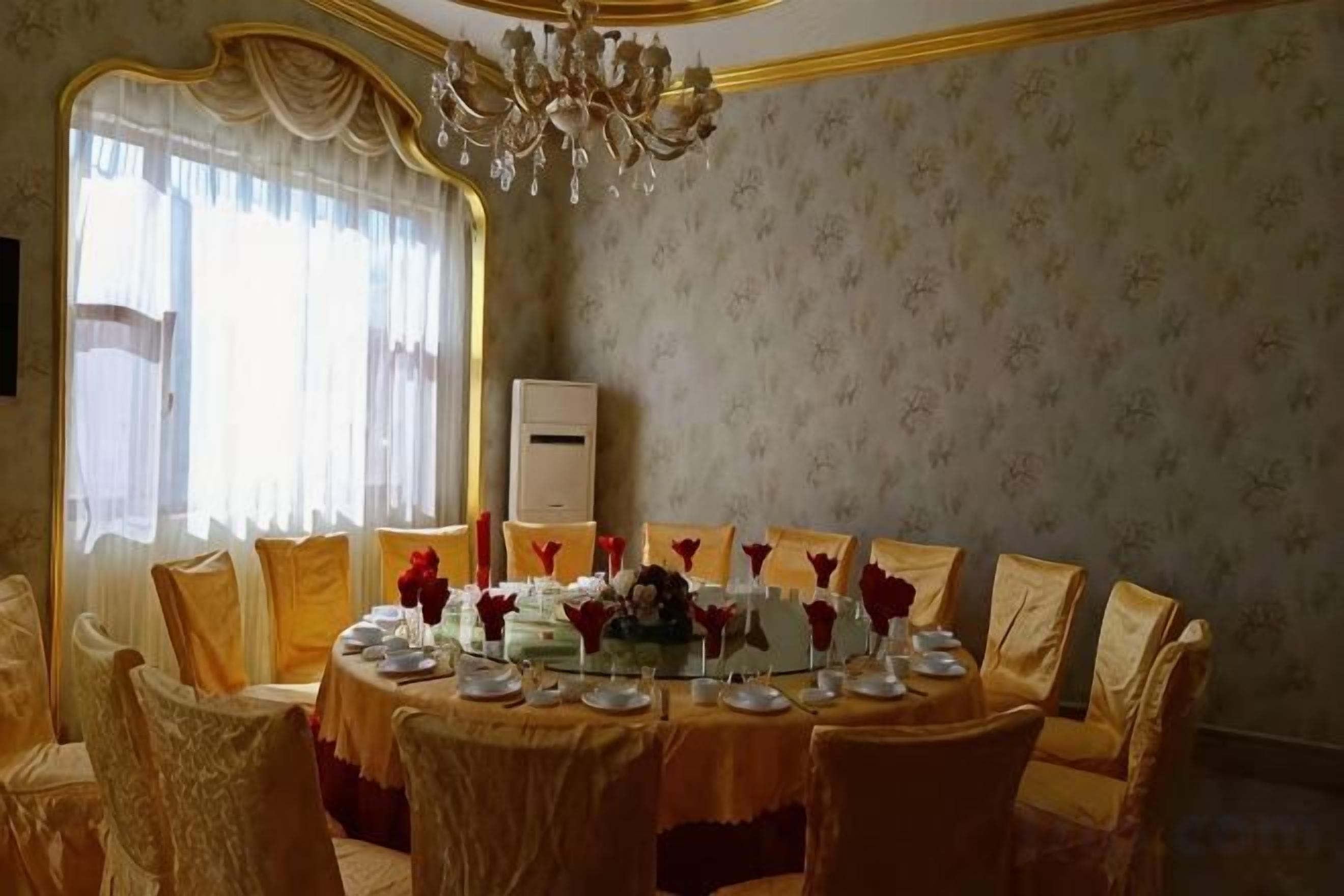 A dining area with a round table set for multiple people, surrounded by chairs.