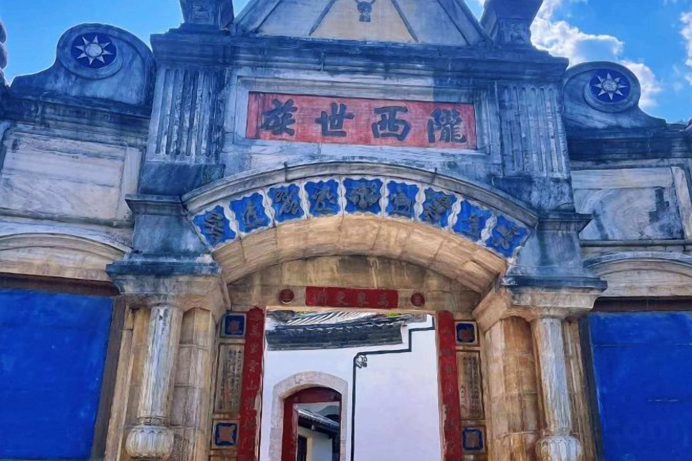 A building entrance with a sign, columns, and a blue door.