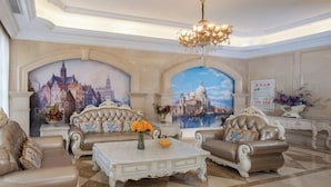 A luxurious living room with ornate furniture, a chandelier, and cityscape murals on the walls. - Vienna Hotel (Puning Huancheng South Road High-speed Railway Station) (Puning)
