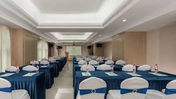 A conference room with rows of tables, chairs, and a presentation screen.