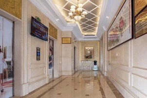 Un pasillo de hotel con candelabro, obras de arte enmarcadas y una zona de recepción.