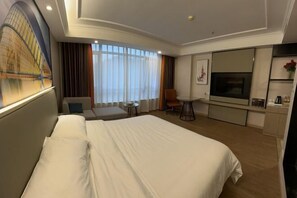 A hotel room with a large bed, a desk, a chair, a TV, and a painting on the wall.