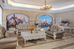 Ein luxuriöses Wohnzimmer mit aufwendigen Sofas, einem weißen Couchtisch und einem Chandelier.