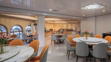 Un espace repas moderne avec des tables rondes, des chaises et un îlot central.