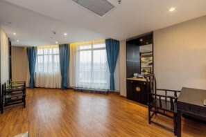 A spacious room with wooden flooring, a dining table with chairs, a small cabinet, and a large window with curtains. - Sanjianghe International Hotel (Pingle)