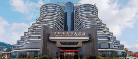 A multi-story hotel with a distinctive curved facade and a central entrance.