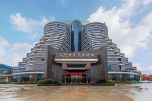 A multi-story hotel with a distinctive curved facade and a central entrance. - Sanjianghe International Hotel (Pingle)