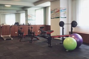 Une salle de sport équipée de matériel d’exercice, d’un banc de musculation et d’un grand ballon d’exercice.