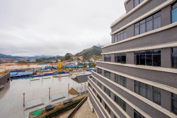 A multi-story building with a flat roof and a view of a construction site in the background.